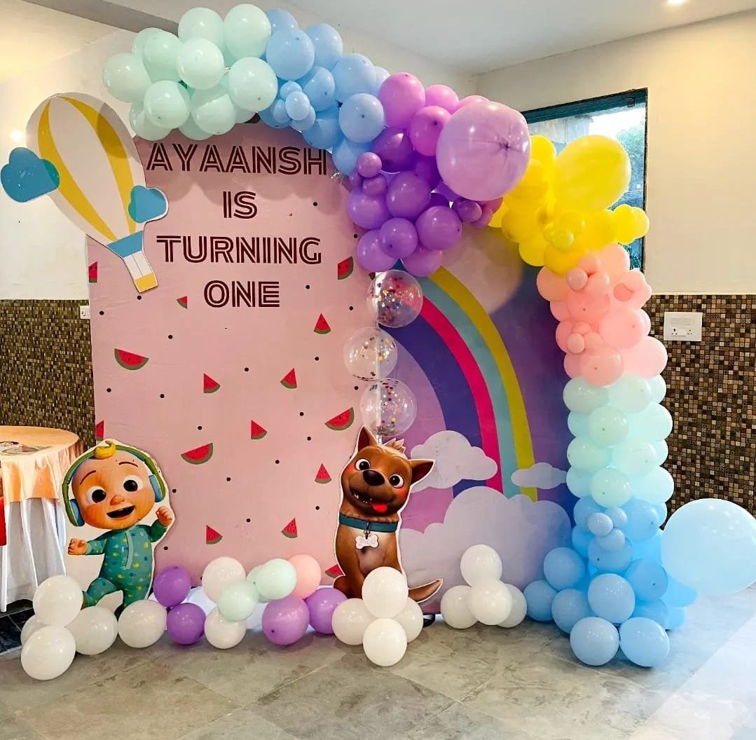 Naming ceremony and first birthday balloon decoration with pastel rainbow backdrop