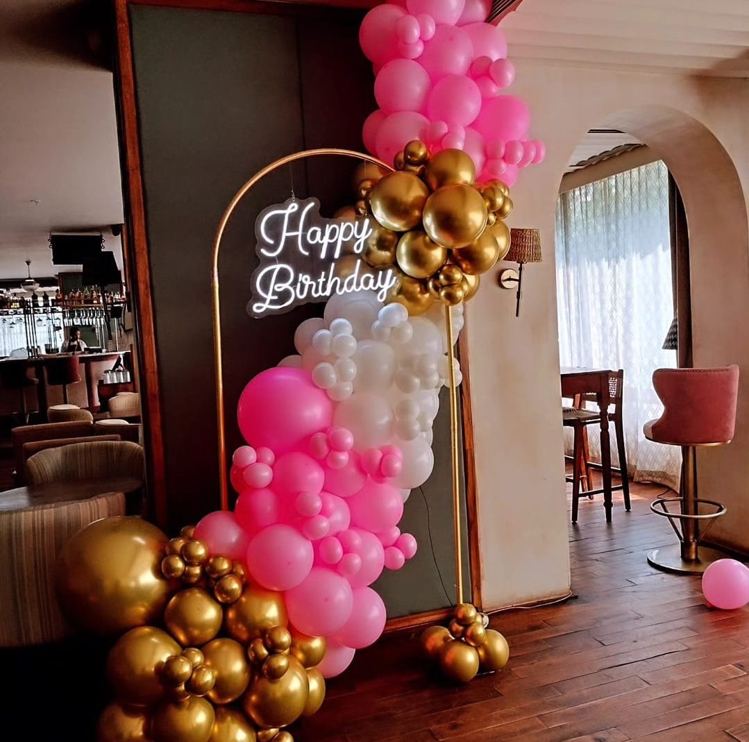Birthday party balloon decor with pink and gold arch and neon sign