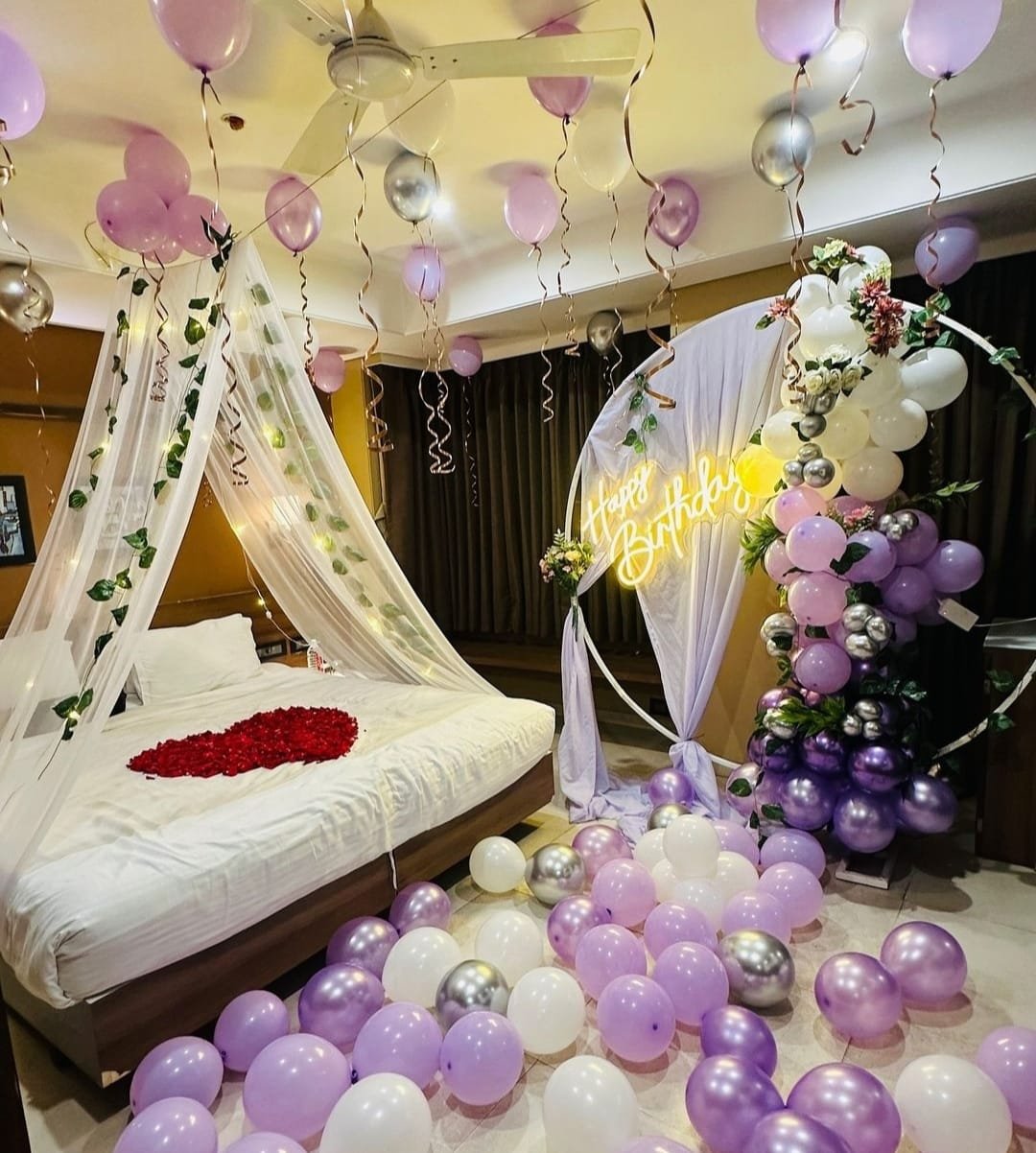 Balloon home decor with ceiling balloons, canopy and rose petal bed setup