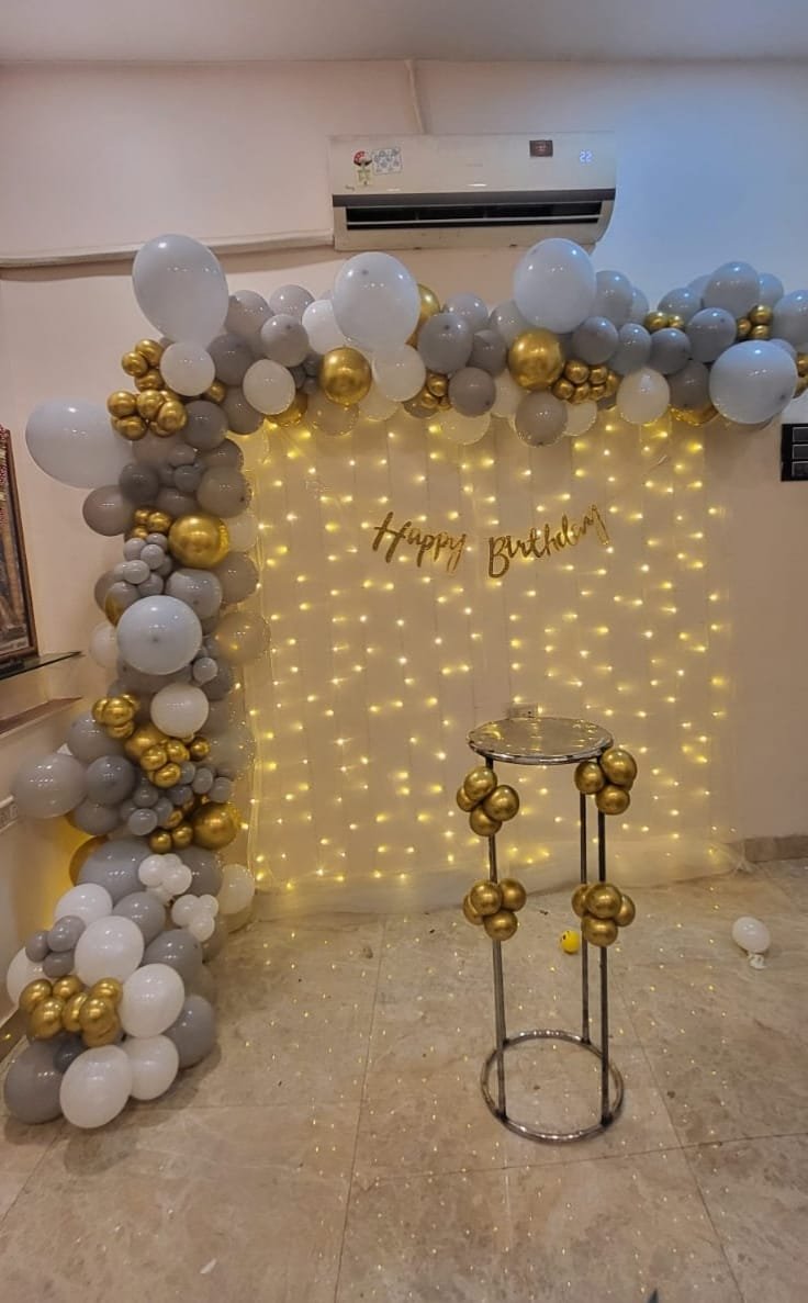 White grey and gold balloon arch with fairy light curtain backdrop